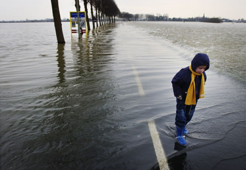 Overstroming straat waar kind in plas staat