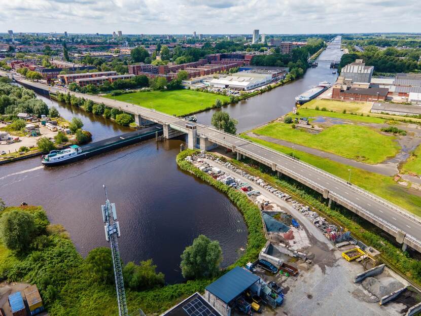 twee vrachtschepen varen op hoofdvaarweg lemmer-delfzijl. Er loopt een busbaan over de vaarweg heen.