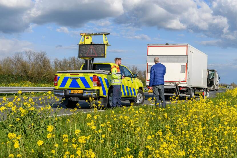 Weginspecteur overlegt met de chauffeur van een defecte vrachtwagen langs de N11. De DRIP van het dienstvoertuig is uit met daarop een waarschuwingsteken.