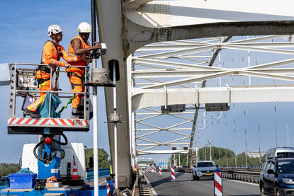 twee mensen voeren werkzaamheden uit aan de Merwedebrug